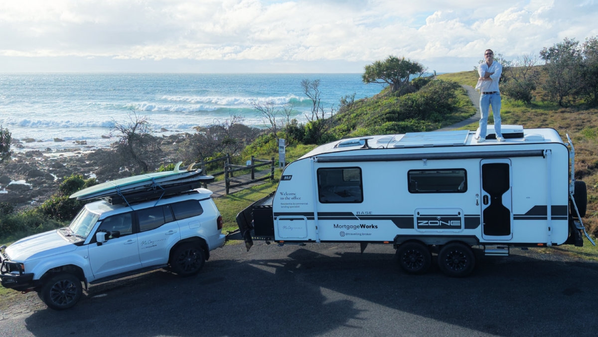 Xavier standing on top of his MortgageWorks caravan by the ocean, ready for the Big Lap