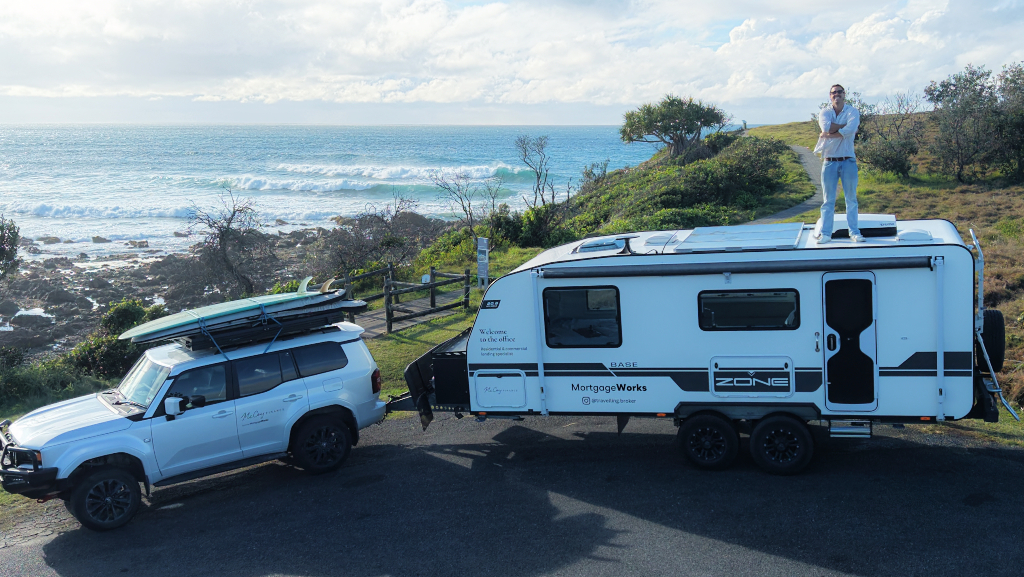 Xavier standing on top of his MortgageWorks caravan by the ocean, ready for the Big Lap