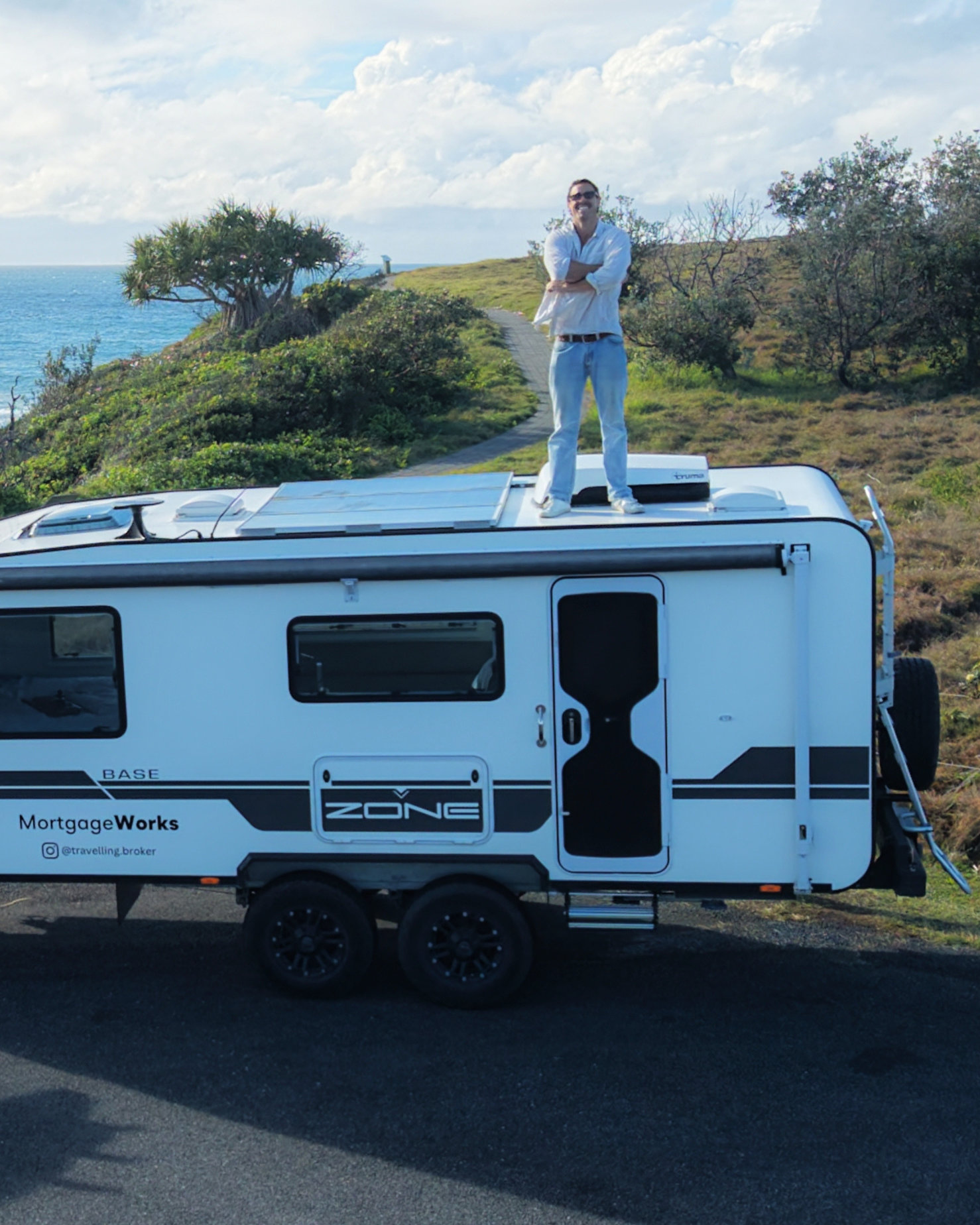 Xavier standing on top of his MortgageWorks caravan overlooking the coastline